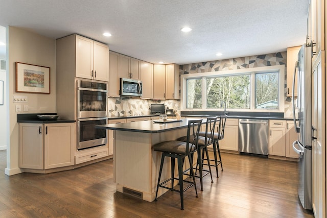 7361 N Shore Dr, South Haven, MI 49090 - kitchen featuring appliances with stainless steel finishes, dark countertops, dark wood-style flooring, a breakfast bar area, and a textured ceiling