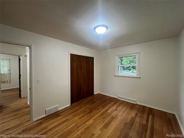 1420 Jones, Port Huron, MI 48060 - unfurnished bedroom with a closet, wood finished floors, baseboards, and a baseboard heating unit