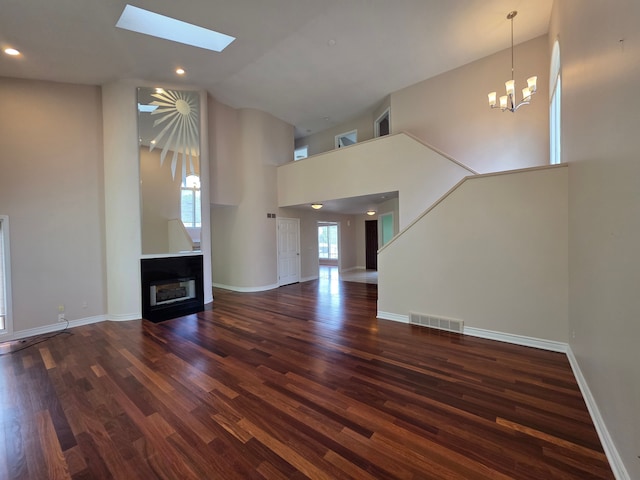 5893 Christina Dr, West Bloomfield, MI 48324 - unfurnished living room featuring high vaulted ceiling, a fireplace, wood finished floors, a skylight, and a chandelier