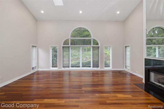 5893 Christina Dr, West Bloomfield, MI 48324 - unfurnished living room with a towering ceiling, wood finished floors, baseboards, a tile fireplace, and recessed lighting
