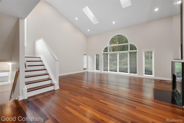 5893 Christina Dr, West Bloomfield, MI 48324 - unfurnished living room featuring high vaulted ceiling, a skylight, wood finished floors, stairway, and a multi sided fireplace