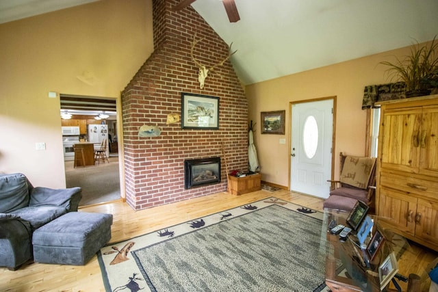 living area with ceiling fan, a fireplace, lofted ceiling, and wood finished floors