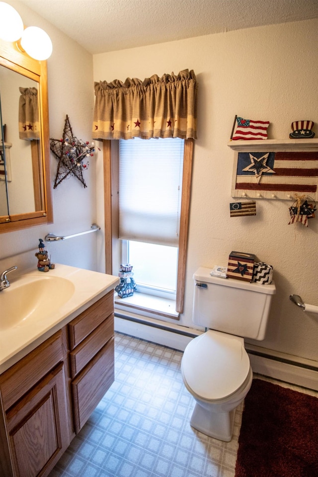 bathroom featuring a baseboard heating unit, tile patterned floors, baseboard heating, toilet, and vanity