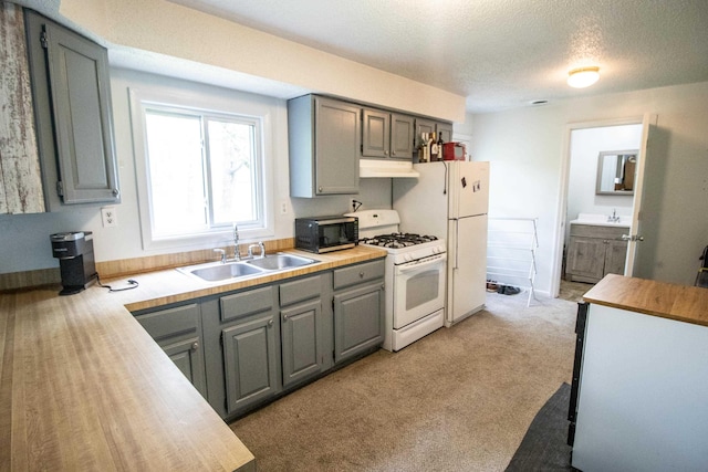 kitchen with white appliances, a sink, gray cabinetry, under cabinet range hood, and a textured ceiling