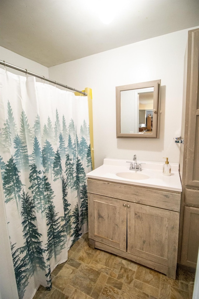 full bath with vanity, a shower with shower curtain, and stone finish floors