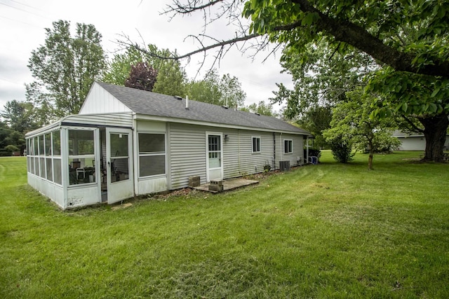 rear view of house featuring a sunroom, a lawn, and a shingled roof