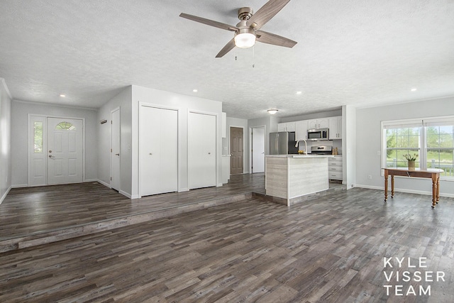 9020 5 Mile Rd NE, Ada, MI 49301 - kitchen with appliances with stainless steel finishes, a sink, open floor plan, a textured ceiling, and dark wood-style flooring