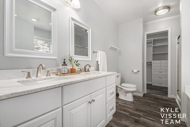 9020 5 Mile Rd NE, Ada, MI 49301 - bathroom featuring wood finished floors, toilet, double vanity, a spacious closet, and baseboards