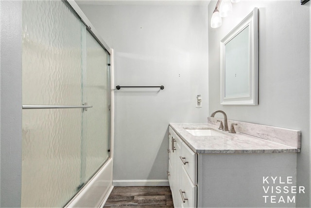 9020 5 Mile Rd NE, Ada, MI 49301 - bathroom with vanity, wood finished floors, bath / shower combo with glass door, and baseboards
