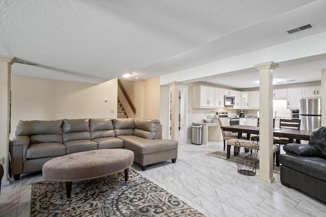 4624 Parman Rd, Stockbridge, MI 49285 - living area with decorative columns, stairs, light marble finish flooring, and a textured ceiling