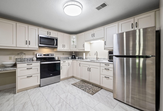4624 Parman Rd, Stockbridge, MI 49285 - kitchen featuring stainless steel appliances, a sink, light marble finish floors, light stone counters, and glass insert cabinets