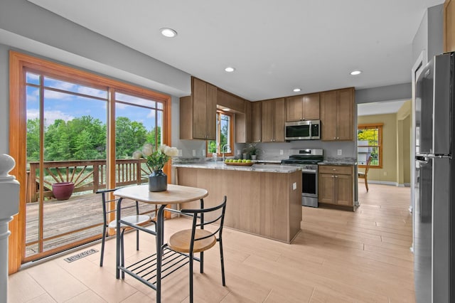 4900 Grass Lake Rd, White Lake, MI 48383 - kitchen with appliances with stainless steel finishes, a peninsula, recessed lighting, light wood-style flooring, and light stone countertops