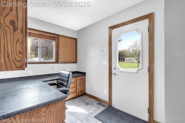 2232 Hayward St, Clio, MI 48420 - kitchen with dark countertops, an office area, brown cabinetry, baseboards, and light tile patterned flooring