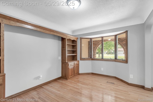 2232 Hayward St, Clio, MI 48420 - spare room with a textured ceiling, light wood-style flooring, baseboards, and arched walkways