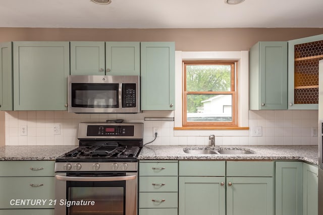 3320 N Sturgeon Rd, Midland, MI 48642 - kitchen featuring green cabinets, appliances with stainless steel finishes, a sink, decorative backsplash, and light stone counters