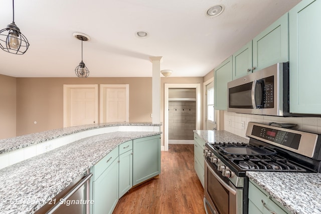 3320 N Sturgeon Rd, Midland, MI 48642 - kitchen with appliances with stainless steel finishes, wood finished floors, hanging light fixtures, backsplash, and baseboards