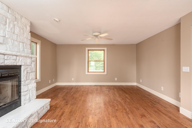 3320 N Sturgeon Rd, Midland, MI 48642 - unfurnished living room featuring wood finished floors, a ceiling fan, a fireplace, and baseboards