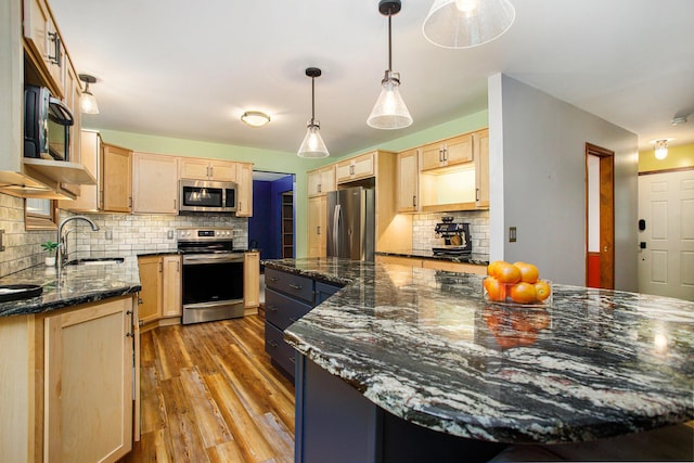 kitchen with appliances with stainless steel finishes, light brown cabinetry, a sink, and light wood finished floors