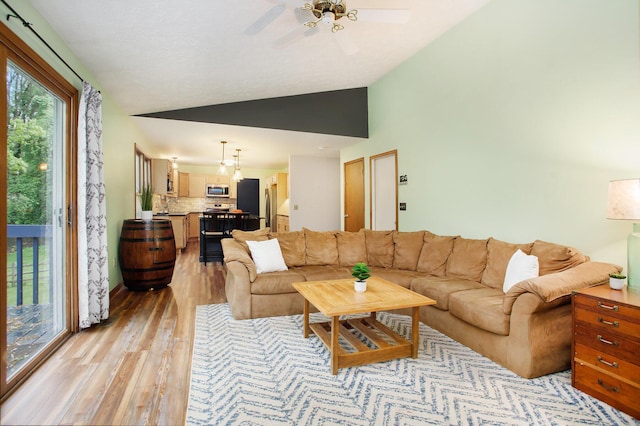 living room with lofted ceiling, light wood-style flooring, and a ceiling fan