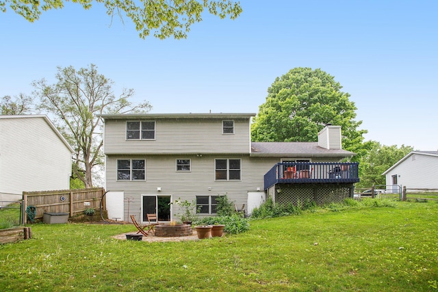 rear view of house with a deck, a chimney, and an outdoor fire pit