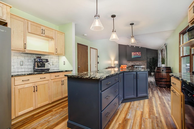 kitchen with light brown cabinetry, light wood-style flooring, backsplash, and vaulted ceiling