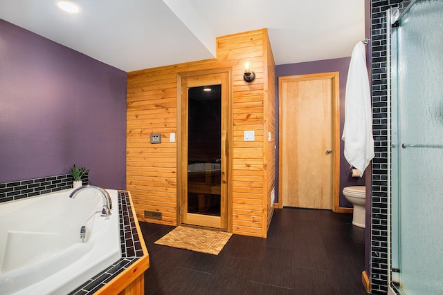 full bath featuring wooden walls, a shower stall, a garden tub, toilet, and recessed lighting