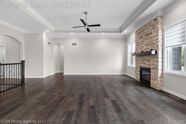 14153 Jode Park, Utica, MI 48315 - unfurnished living room with ceiling fan, arched walkways, dark wood-style flooring, a stone fireplace, and a tray ceiling