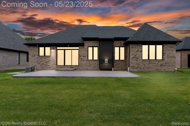 14153 Jode Park, Utica, MI 48315 - back of house at dusk with a patio area, brick siding, a lawn, central AC, and roof with shingles