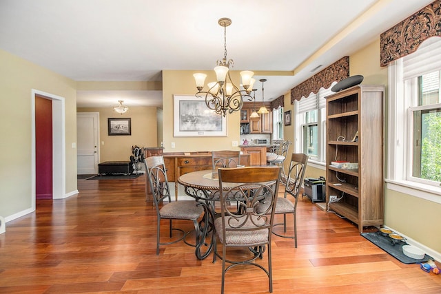dining area featuring a chandelier, plenty of natural light, and wood finished floors