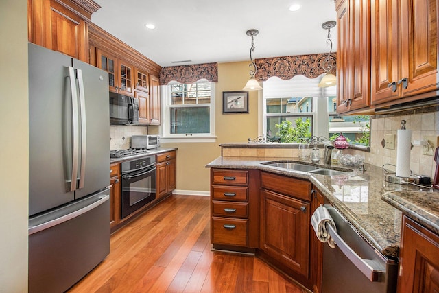 kitchen with black appliances, a sink, wood-type flooring, decorative backsplash, and brown cabinets