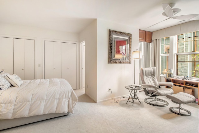 bedroom featuring two closets, light colored carpet, baseboards, and ceiling fan