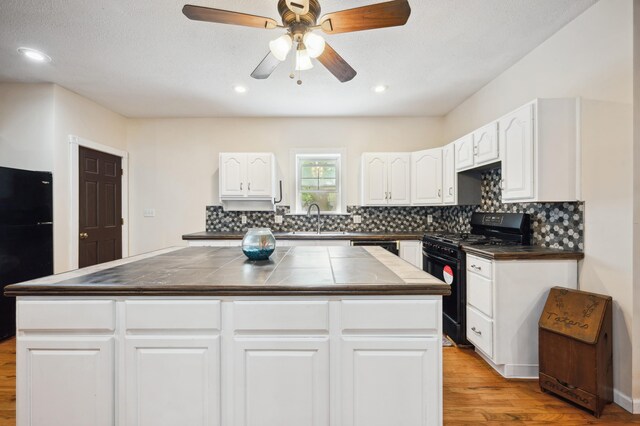 113 W Chicago St, Buchanan, MI 49107 - kitchen with black appliances, light wood-type flooring, a sink, a center island, and decorative backsplash