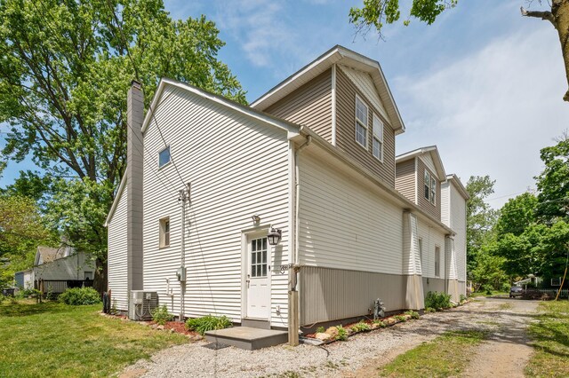 113 W Chicago St, Buchanan, MI 49107 - view of side of home featuring cooling unit, a chimney, dirt driveway, and a lawn