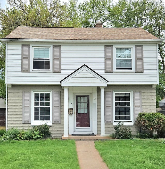 1381 Brys Dr, Grosse Pointe Woods, MI 48236 - colonial inspired home with a chimney, brick siding, and a front lawn