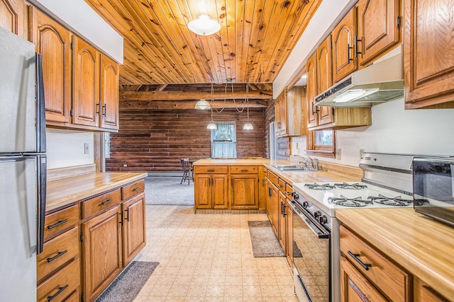 kitchen with gas range oven, a sink, under cabinet range hood, freestanding refrigerator, and wooden ceiling