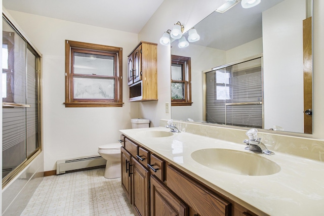 bathroom with baseboard heating, toilet, baseboards, double vanity, and enclosed tub / shower combo