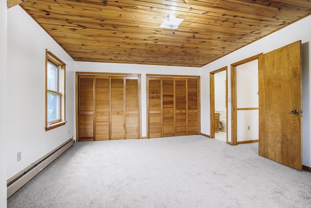 unfurnished bedroom with baseboard heating, wooden ceiling, carpet, two closets, and ensuite bathroom