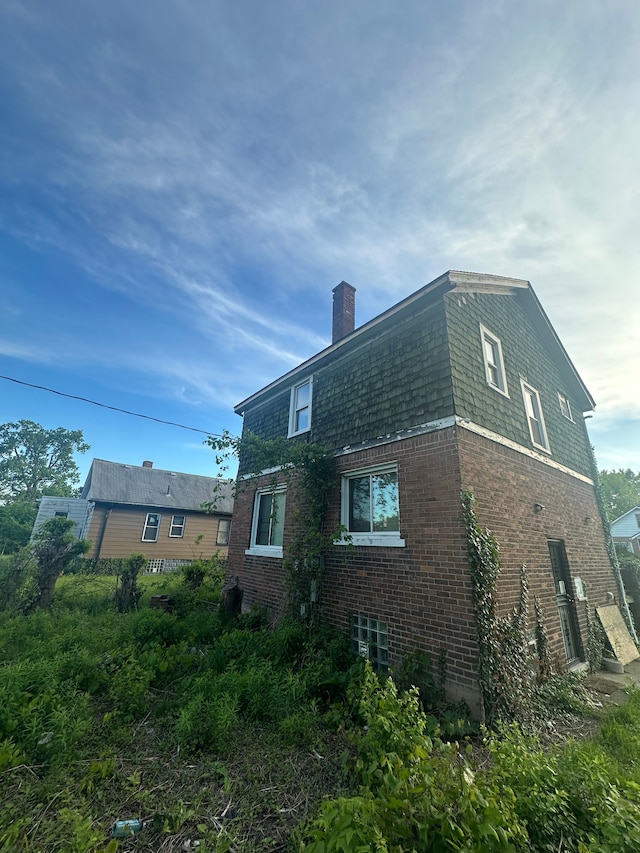 17532 Russell St, Highland Park, MI 48203 - view of property exterior with brick siding, a chimney, and mansard roof