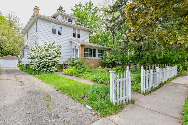 view of front of house featuring an outbuilding, a chimney, driveway, a detached garage, and brick siding