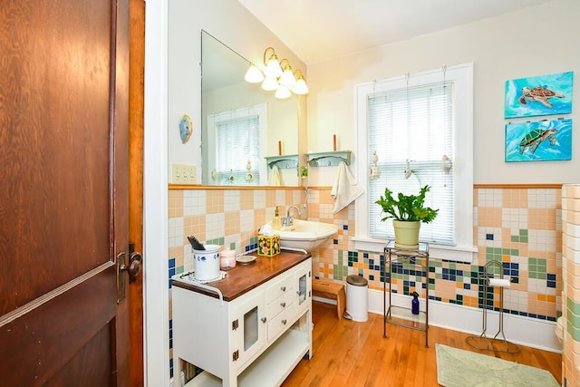 bathroom with tile walls, a sink, wood finished floors, and wainscoting
