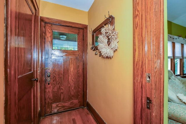 doorway with wood finished floors and baseboards