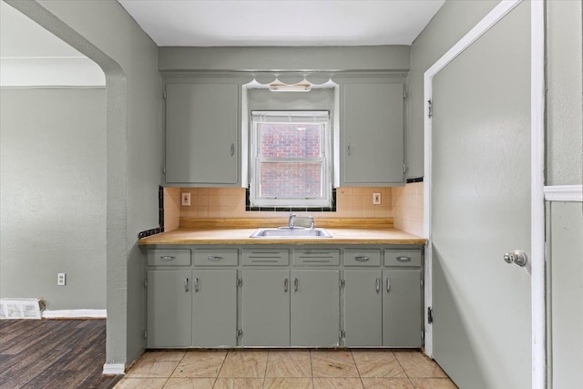 6905 Archdale St, Detroit, MI 48228 - kitchen featuring a sink, backsplash, light countertops, and gray cabinetry