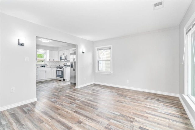 15016 Sunbury St, Livonia, MI 48154 - unfurnished living room featuring a sink, light wood-type flooring, and baseboards
