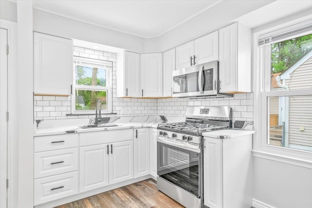 15016 Sunbury St, Livonia, MI 48154 - kitchen with stainless steel appliances, a sink, light countertops, white cabinets, and decorative backsplash
