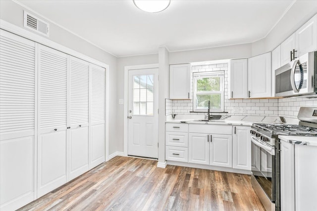 15016 Sunbury St, Livonia, MI 48154 - kitchen with stainless steel appliances, light countertops, tasteful backsplash, a sink, and ornamental molding