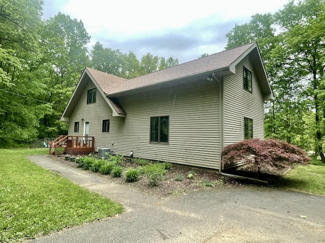 19490 Island Lake Rd, Chelsea, MI 48118 - view of home's exterior featuring central AC unit, a shingled roof, and a lawn