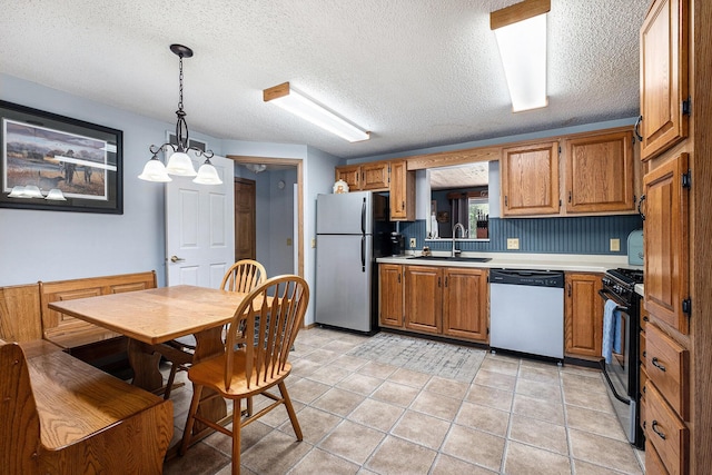 4171 E 124th St, Grant, MI 49327 - kitchen featuring stainless steel appliances, a sink, light countertops, brown cabinetry, and decorative light fixtures