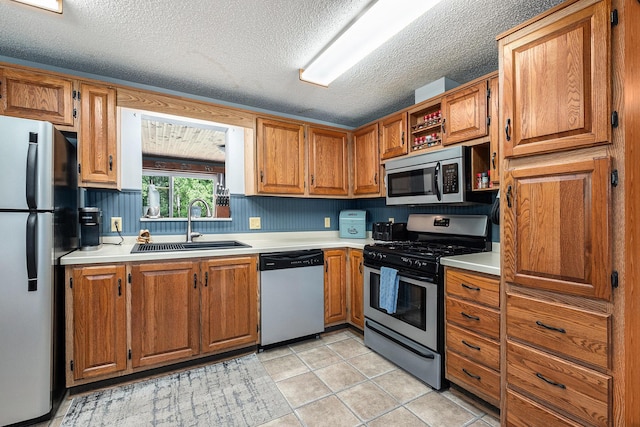 4171 E 124th St, Grant, MI 49327 - kitchen featuring appliances with stainless steel finishes, a sink, light countertops, brown cabinets, and a textured ceiling