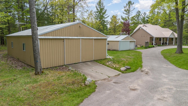 5511 Westside Dr, Alger, MI 48610 - view of home's exterior featuring a detached garage, an outbuilding, a yard, and view of wooded area