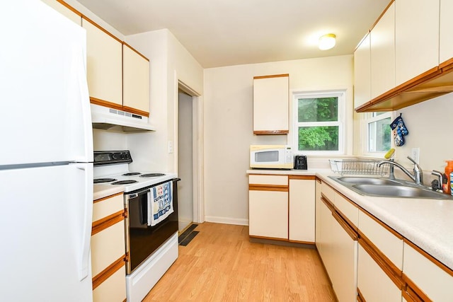 kitchen featuring under cabinet range hood, white appliances, a sink, light wood finished floors, and light countertops